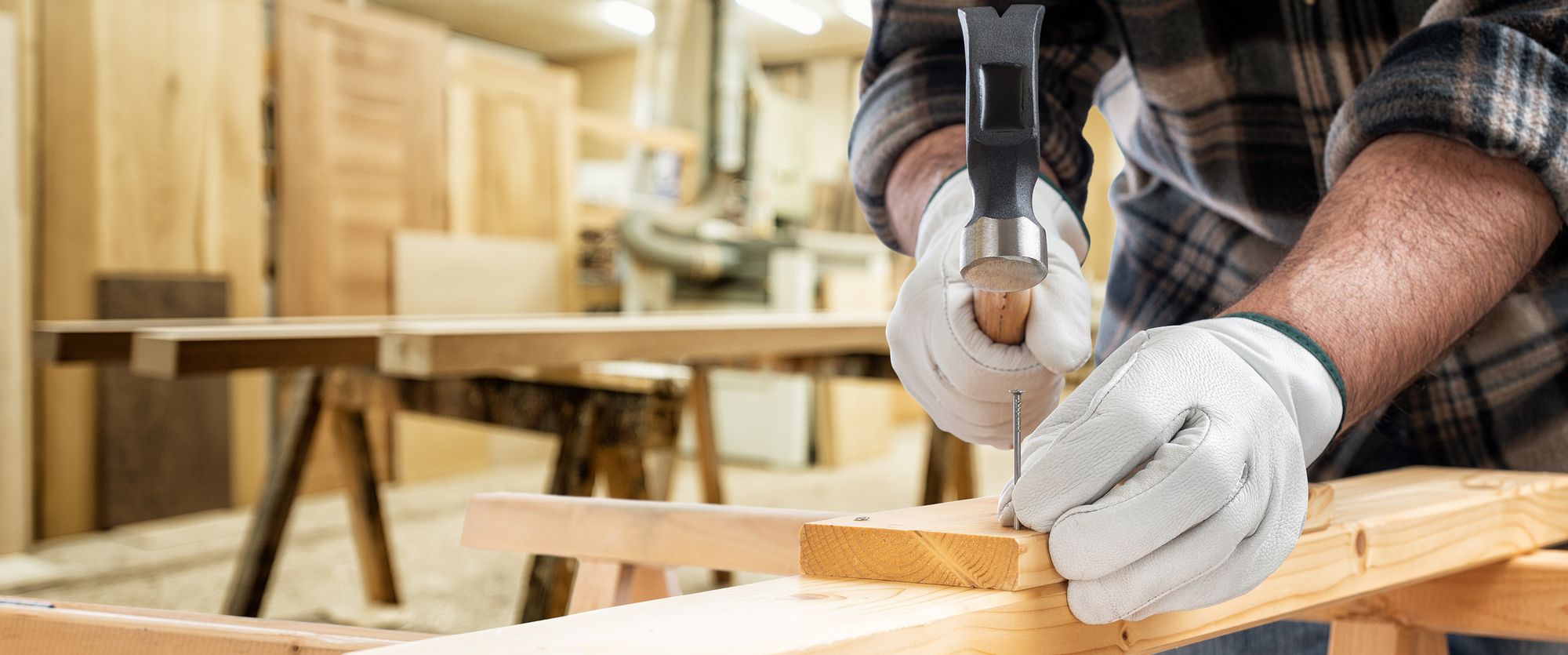 Ein Schreiner haut einen Nagel in ein Stück Holz
